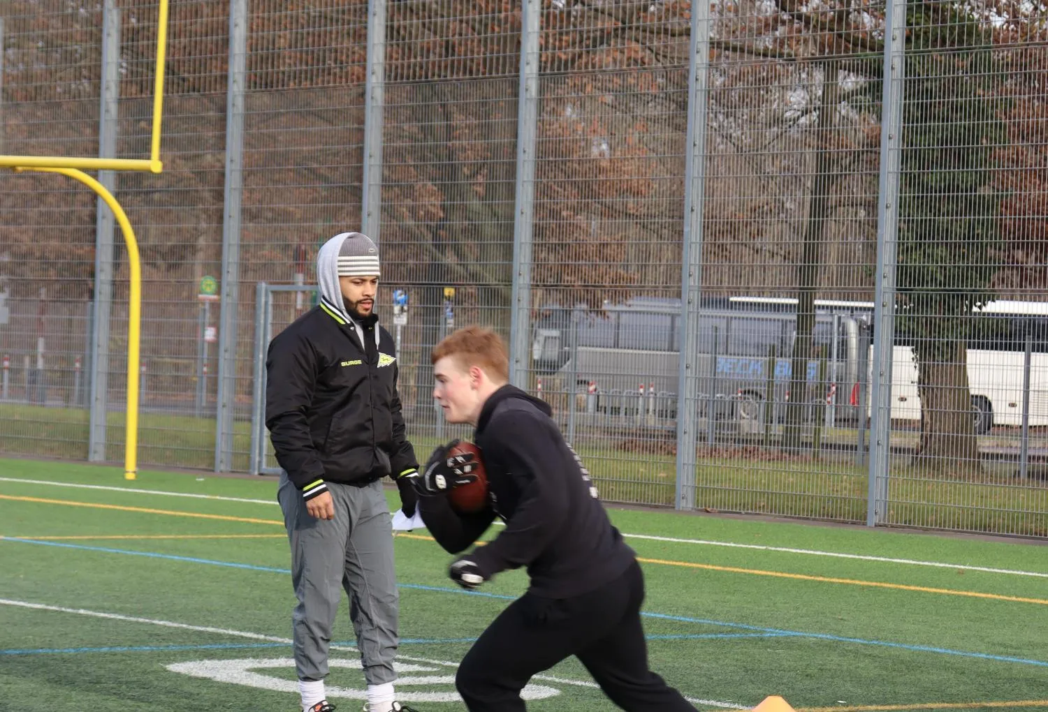 Kai Hunter coaching a young running back through a drill on the field